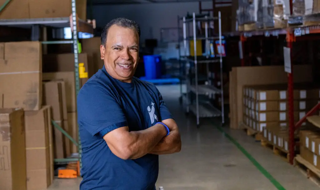 Cleaner standing in a warehouse with arms crossed in heroic pose